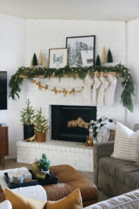 Create a Cozy and Modern Holiday Look with Live Green Garlands, Dried Orange Slices, Neutral Decor, and Touches of Metallic Golds.